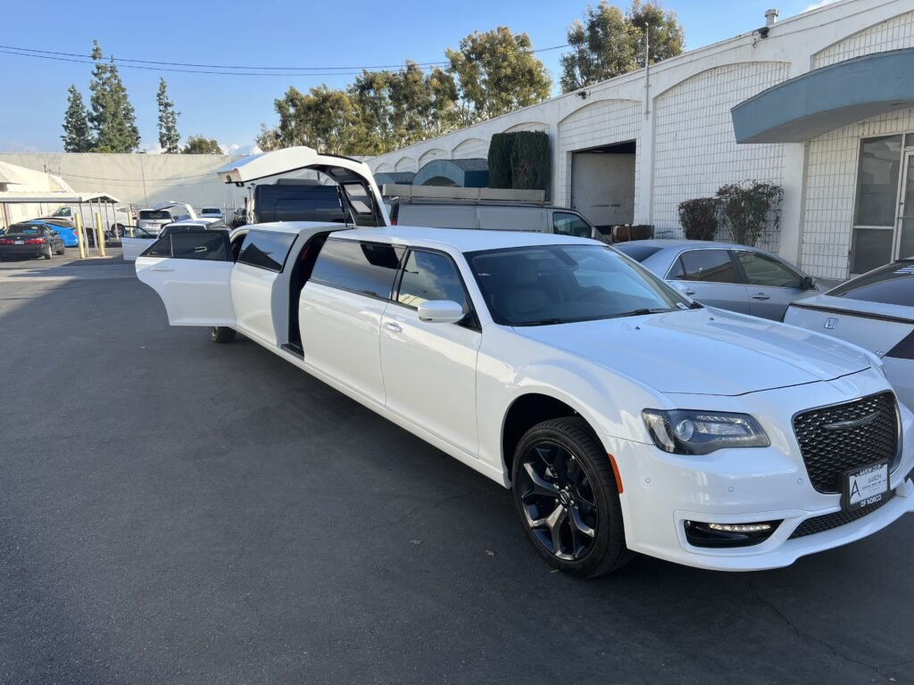 White Chrysler 300 stretch limousine with open doors and trunk parked outside building in Summit, NJ