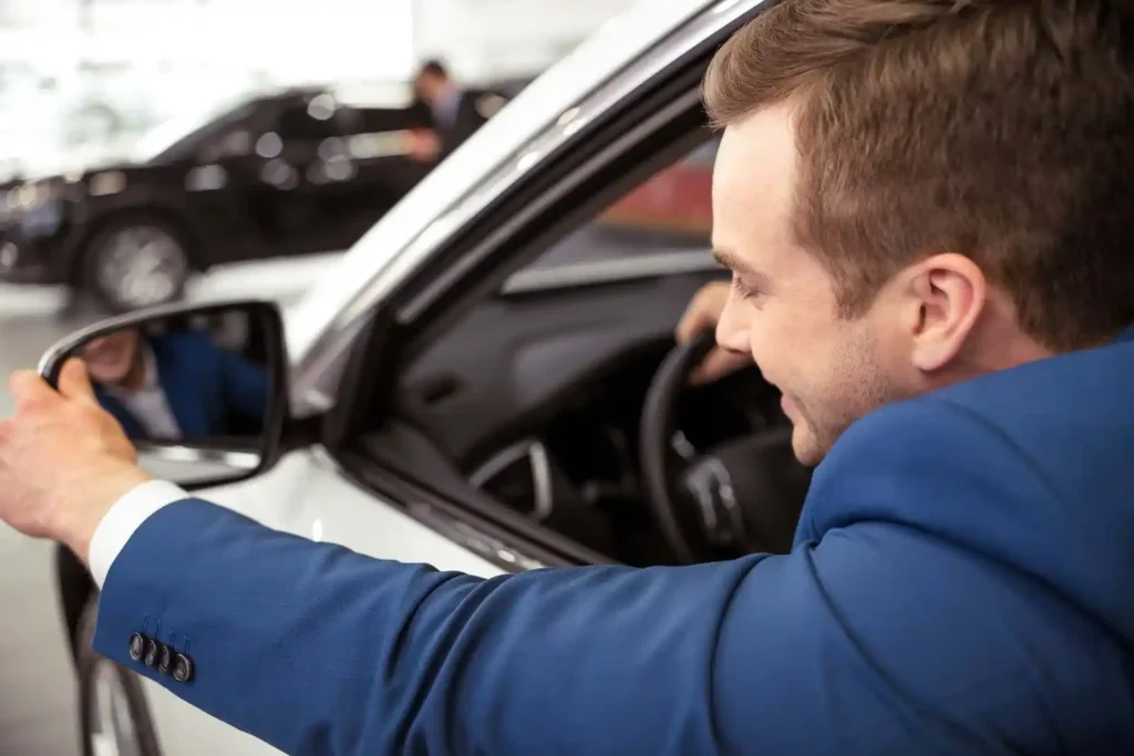 Chauffeur in blue suit adjusting mirror of white luxury car in Summit NJ
